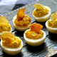 Deviled eggs with a potato chip garnish on a black plate